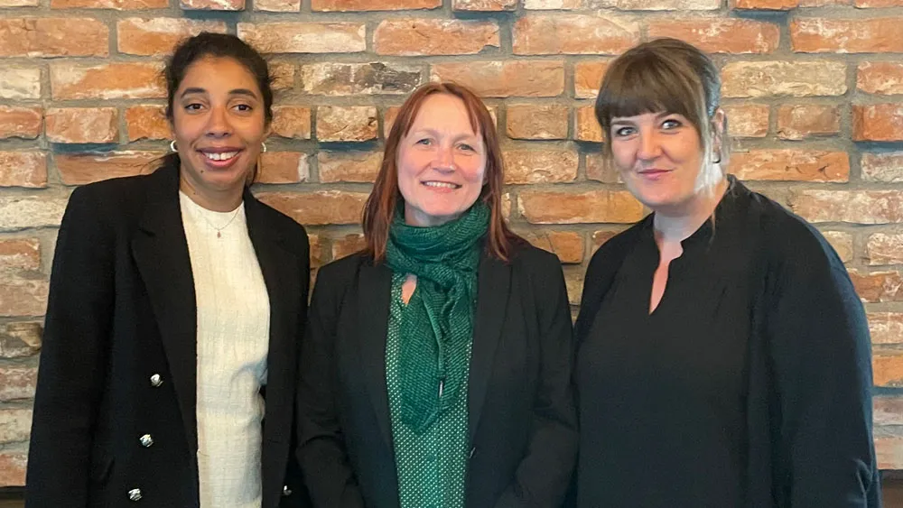 Three women standing in front of a wall