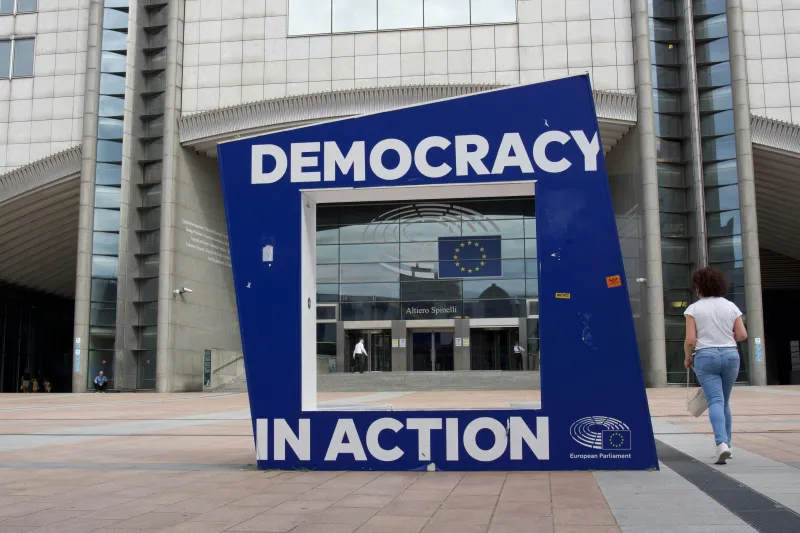 EU Parliament in Brussels with a sign in front saying Democracy in Action
