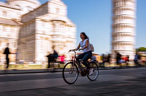 Student riding a bike under the leaning Tower