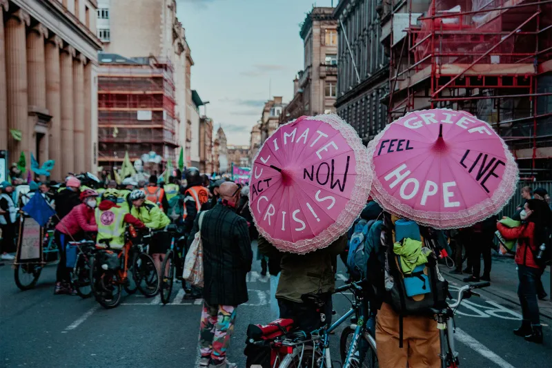 Group of people walking down a street with pink umbrellas