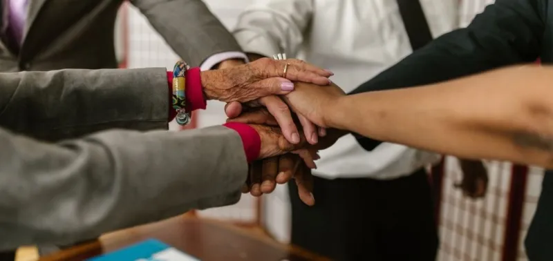 Group of people linking hands. Credits: RDNE