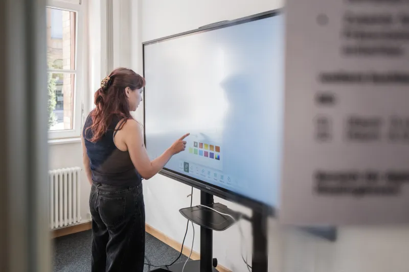 A person standing facing a smart board. 