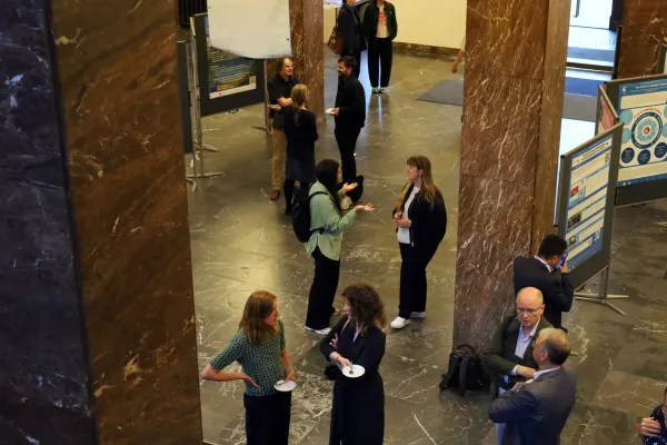 People standing among the posters of the exhibition, chatting.