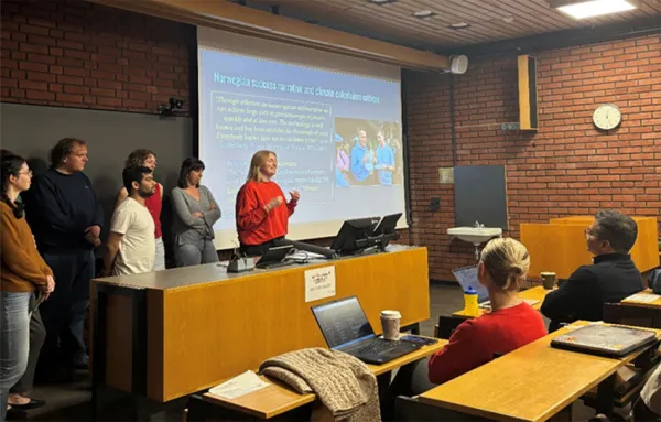 Six students presenting their work in an auditorium.