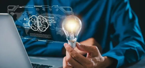 Person sitting at laptop holding a lightbulb