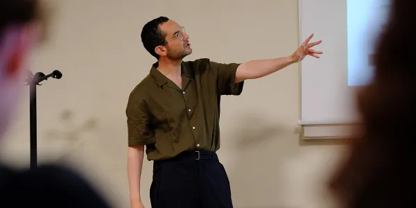 Professor teaching in a classroom, pointing to content on a whiteboard during a lecture.